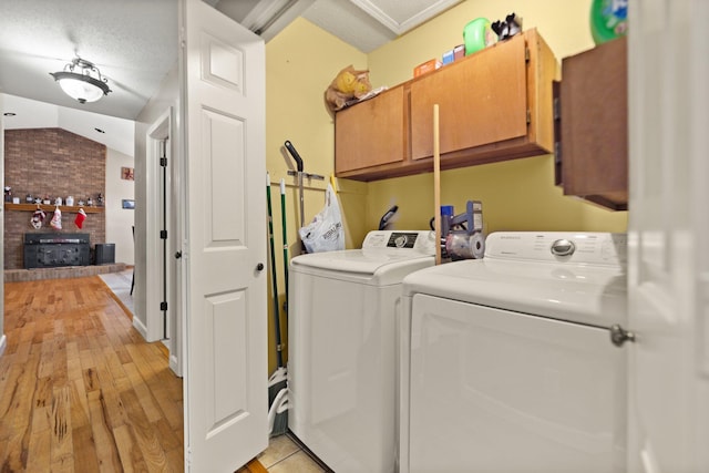 washroom featuring a textured ceiling, cabinets, independent washer and dryer, and light wood-type flooring