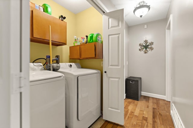 washroom featuring cabinets, light hardwood / wood-style floors, and washer and dryer