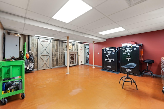 interior space featuring a barn door and a drop ceiling