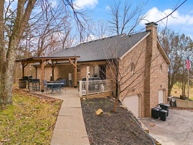 rear view of house featuring covered porch, a patio, and a garage