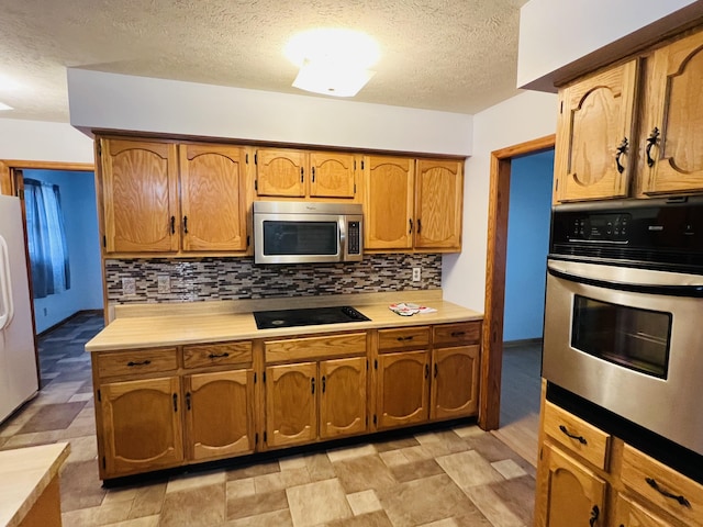 kitchen featuring decorative backsplash, a textured ceiling, and appliances with stainless steel finishes