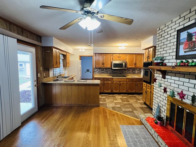 kitchen with light wood-type flooring, kitchen peninsula, sink, and appliances with stainless steel finishes