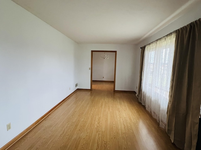 unfurnished room featuring light wood-type flooring and an inviting chandelier