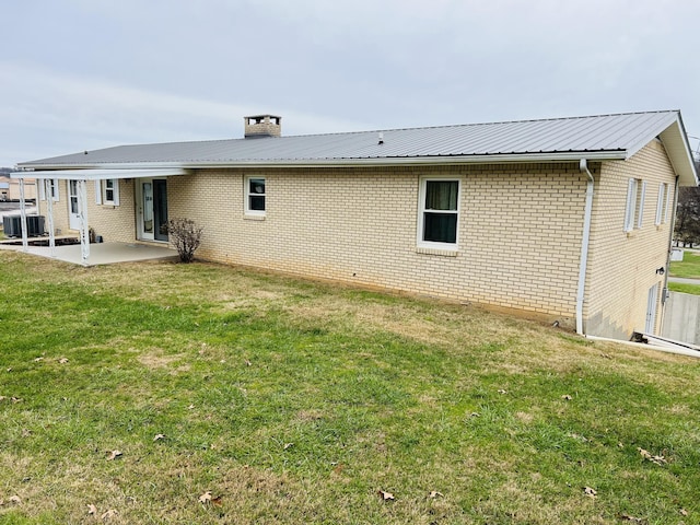 rear view of house with a lawn, cooling unit, and a patio