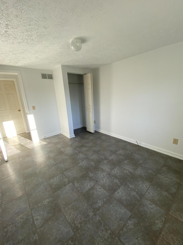 unfurnished bedroom featuring a textured ceiling and a closet