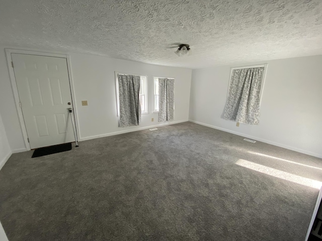 unfurnished room featuring dark colored carpet and a textured ceiling