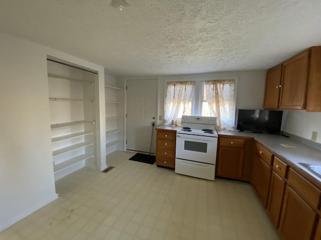 kitchen featuring a textured ceiling, white electric stove, and sink