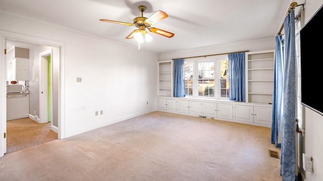 interior space with light colored carpet, ceiling fan, and crown molding