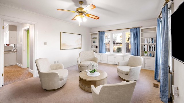 sitting room with light carpet, ceiling fan, and crown molding