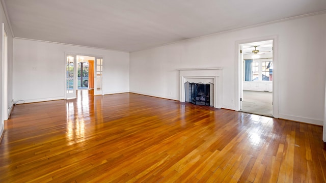 unfurnished living room featuring hardwood / wood-style floors, plenty of natural light, crown molding, and ceiling fan