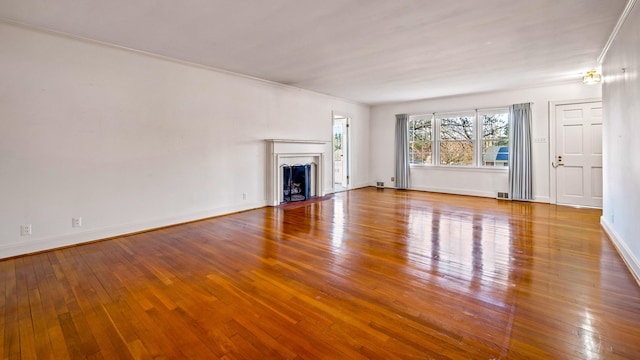 unfurnished living room featuring wood-type flooring and ornamental molding