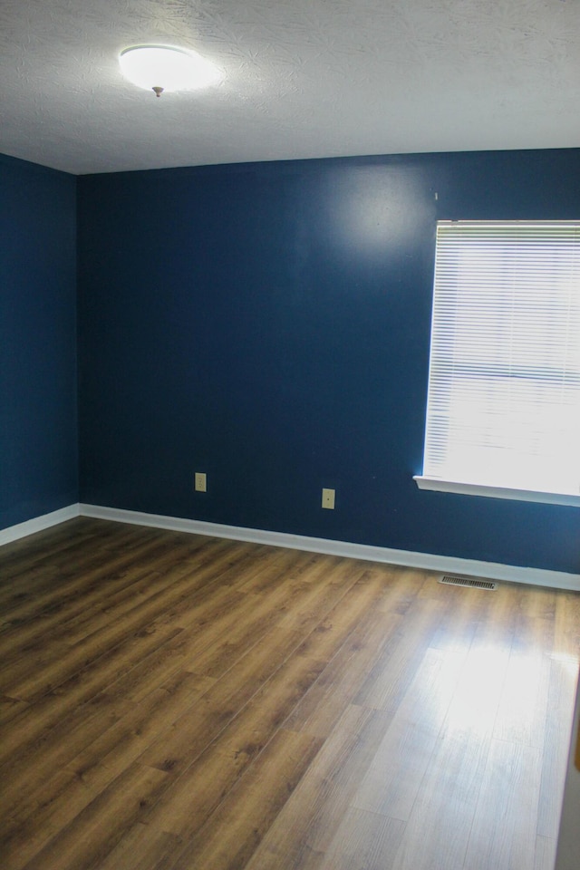 empty room featuring a textured ceiling and hardwood / wood-style flooring