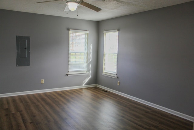 spare room featuring a textured ceiling, electric panel, dark hardwood / wood-style floors, and ceiling fan