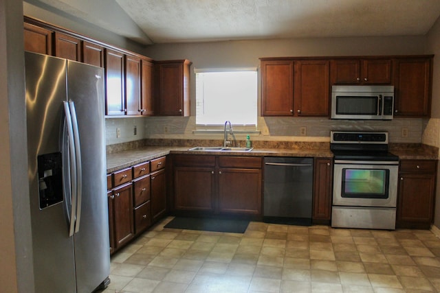 kitchen with tasteful backsplash, sink, stainless steel appliances, and vaulted ceiling