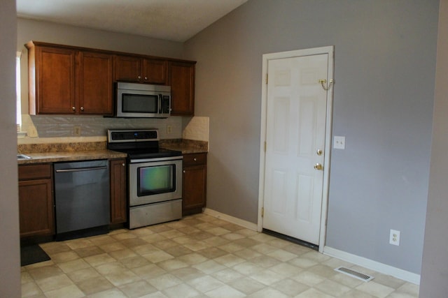 kitchen with decorative backsplash, stainless steel appliances, and vaulted ceiling