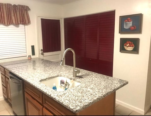 kitchen featuring a center island, dishwasher, sink, light stone counters, and light tile patterned flooring