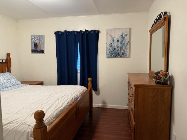 bedroom featuring ornamental molding and dark wood-type flooring