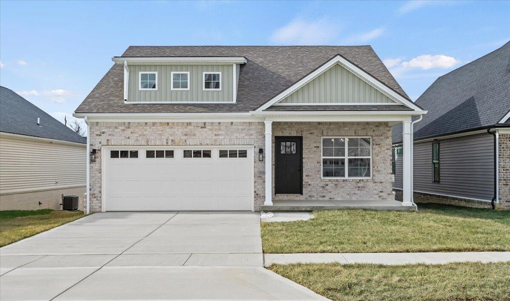 view of front of home featuring a front yard, a garage, central AC unit, and covered porch