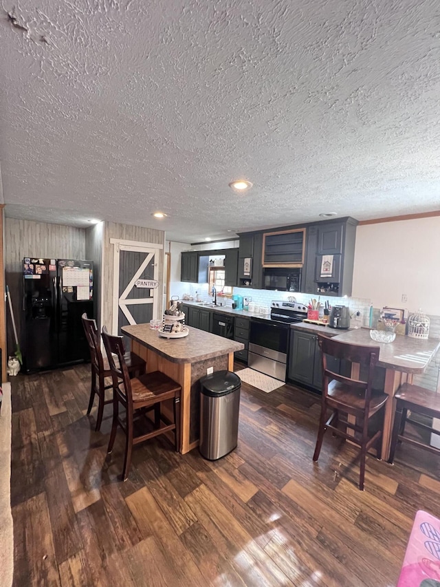 kitchen featuring sink, dark wood-type flooring, stainless steel range with electric stovetop, a textured ceiling, and black fridge with ice dispenser