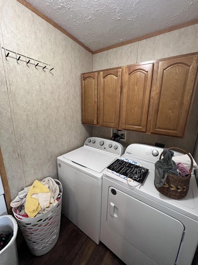 laundry area with cabinets, a textured ceiling, crown molding, washing machine and clothes dryer, and dark hardwood / wood-style floors