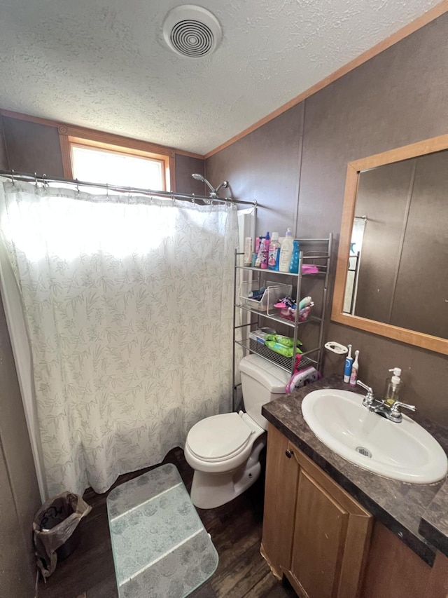 bathroom with hardwood / wood-style floors, vanity, toilet, walk in shower, and a textured ceiling