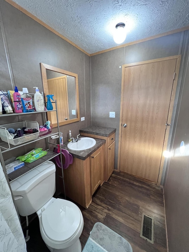 bathroom featuring hardwood / wood-style flooring, vanity, toilet, and a textured ceiling