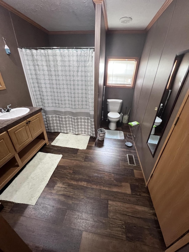 bathroom with crown molding, wood-type flooring, a textured ceiling, toilet, and vanity