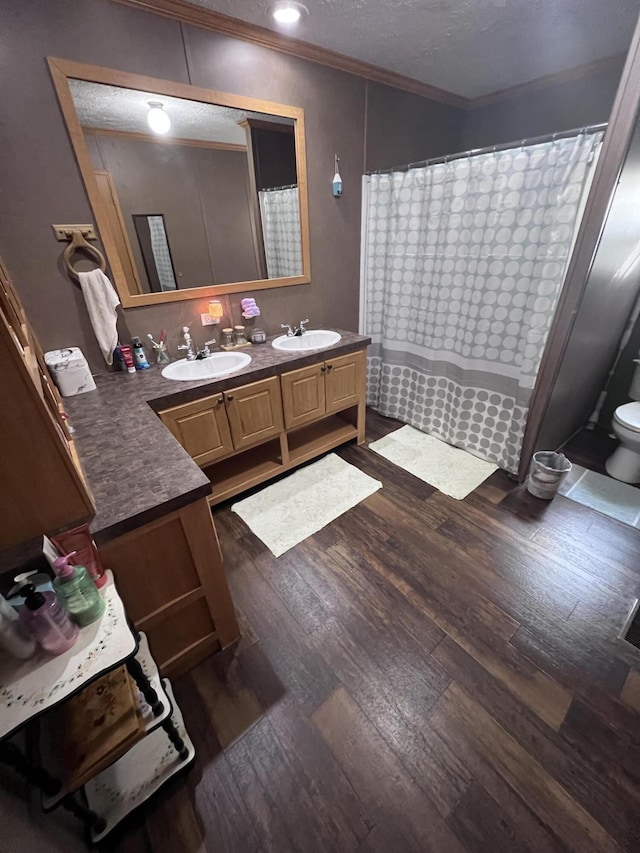 bathroom featuring vanity, a shower with curtain, hardwood / wood-style flooring, toilet, and ornamental molding