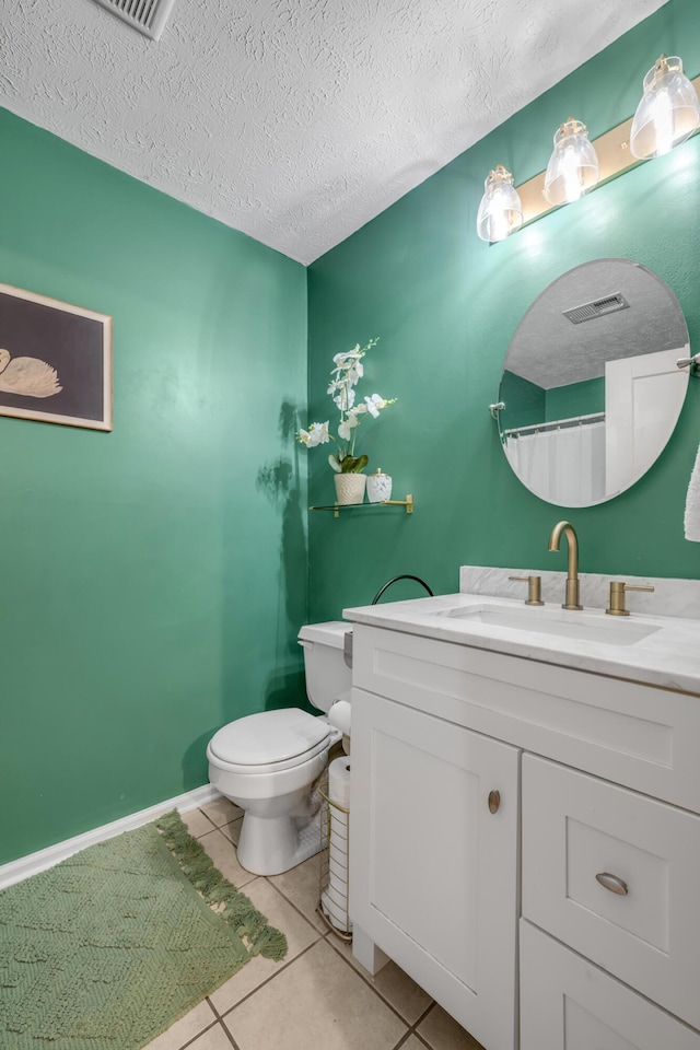 bathroom featuring tile patterned flooring, vanity, a textured ceiling, and toilet