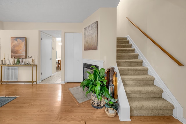 staircase with hardwood / wood-style flooring and heating unit