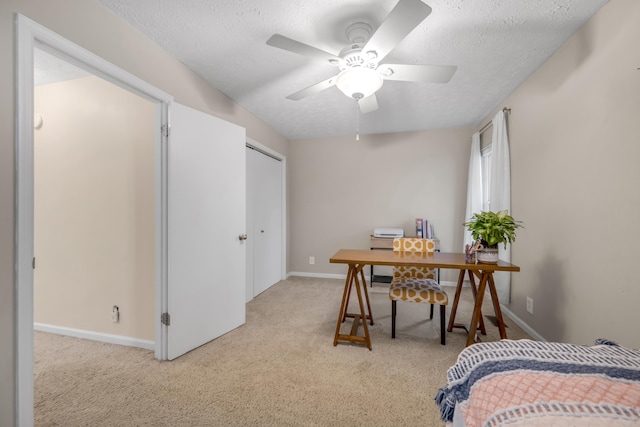 carpeted office space with a textured ceiling and ceiling fan