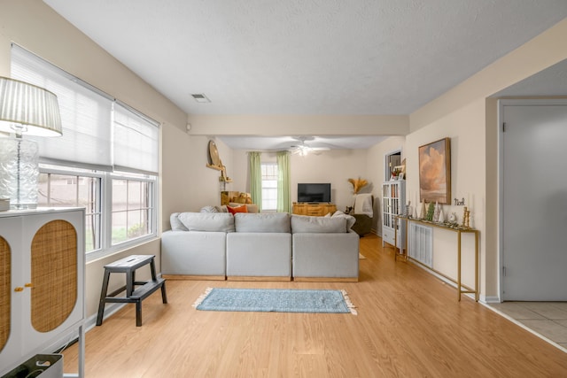 living room featuring a wealth of natural light, ceiling fan, a textured ceiling, and light wood-type flooring