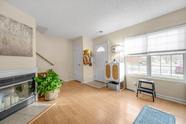 foyer entrance with light hardwood / wood-style floors and a textured ceiling