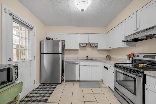 kitchen with sink, stainless steel appliances, white cabinets, a textured ceiling, and light tile patterned flooring