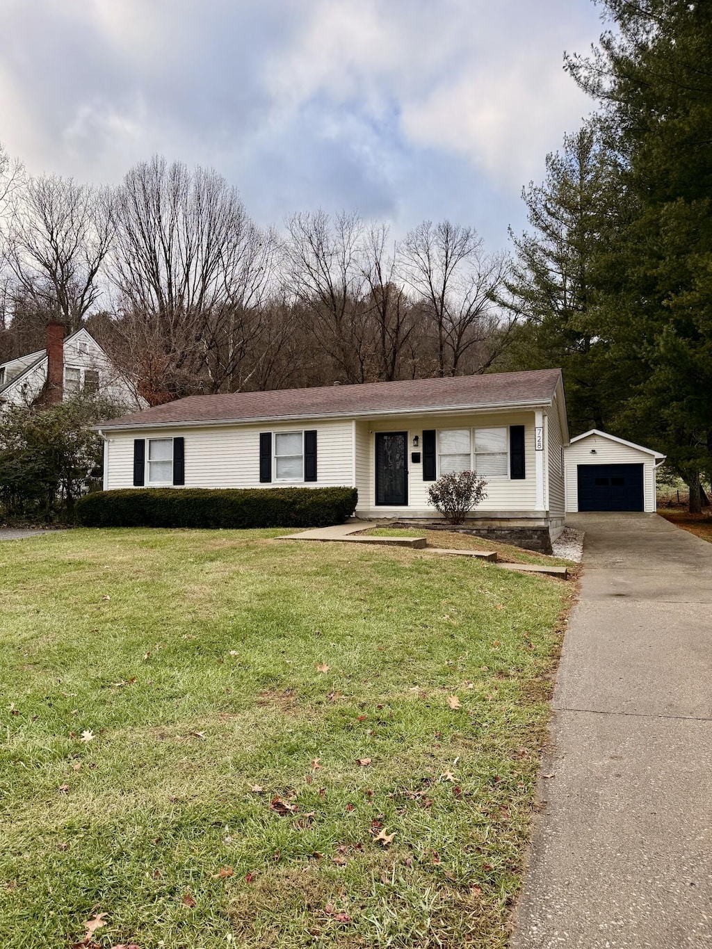 view of front of property with a garage, an outdoor structure, and a front yard