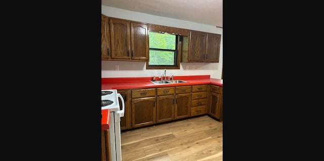 kitchen with white range with electric cooktop, sink, and light wood-type flooring