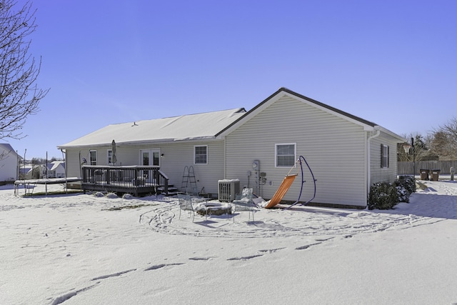 snow covered rear of property featuring a wooden deck, cooling unit, and an outdoor fire pit