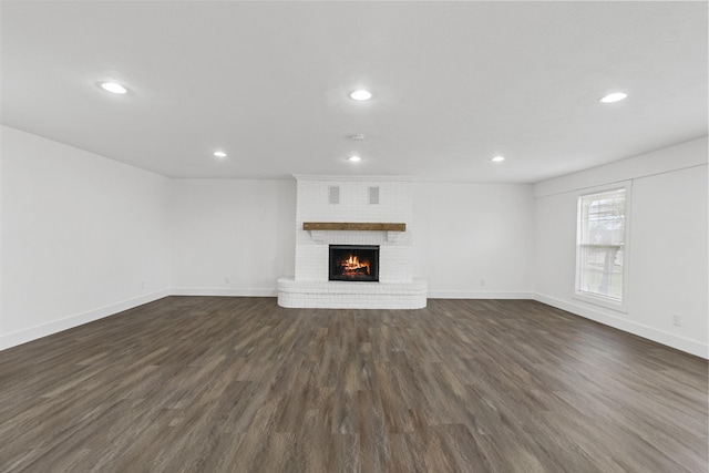 unfurnished living room featuring dark hardwood / wood-style floors and a brick fireplace