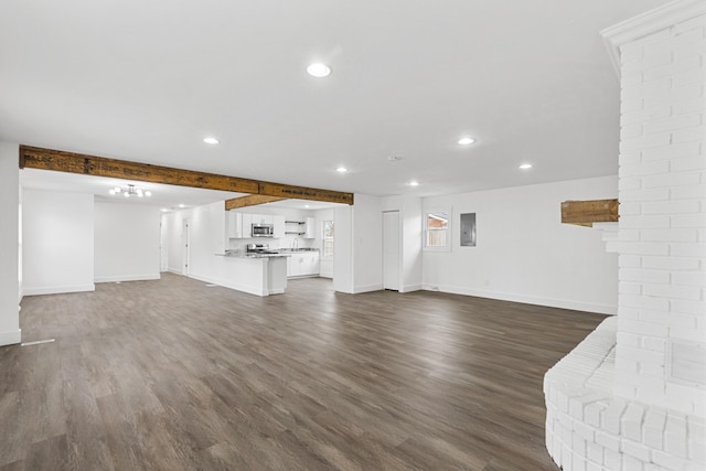 unfurnished living room with beamed ceiling, dark hardwood / wood-style flooring, and electric panel