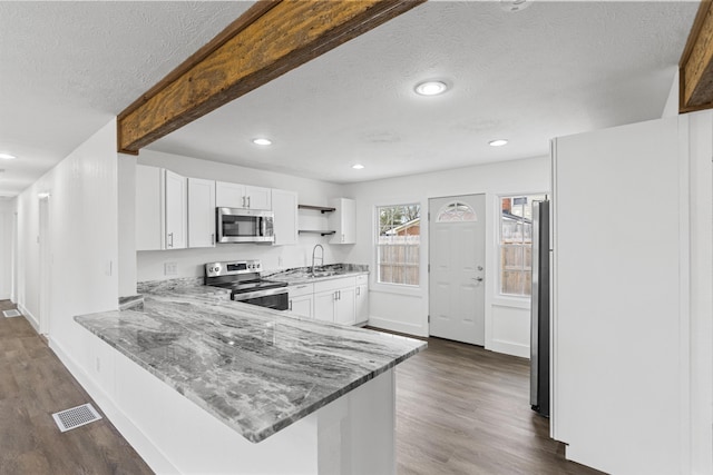 kitchen featuring white cabinets, appliances with stainless steel finishes, kitchen peninsula, and light stone counters