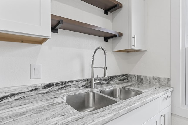 kitchen with light stone counters, sink, and white cabinets