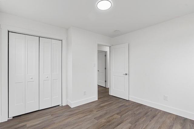 unfurnished bedroom featuring a closet and dark wood-type flooring