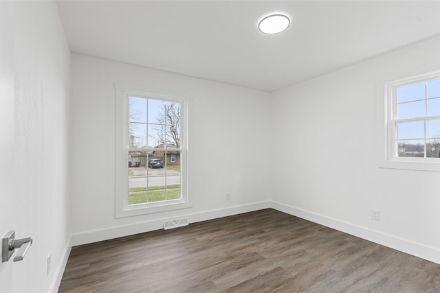 empty room featuring a healthy amount of sunlight and dark hardwood / wood-style floors