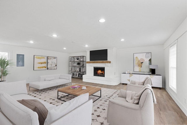 living room with electric panel, a fireplace, and light wood-type flooring