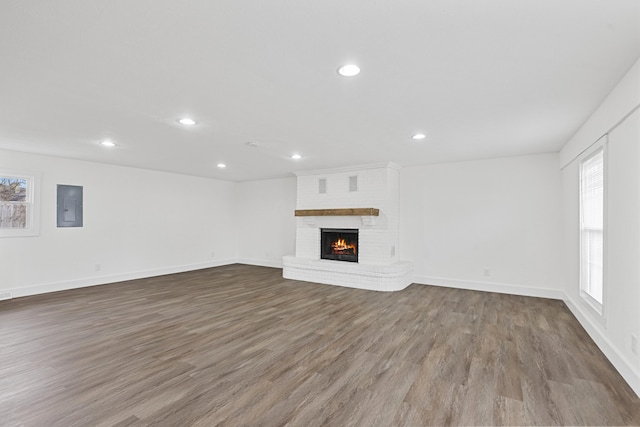 unfurnished living room with wood-type flooring, a fireplace, and electric panel