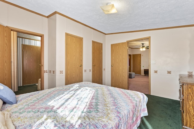 carpeted bedroom featuring a textured ceiling, vaulted ceiling, multiple closets, and crown molding