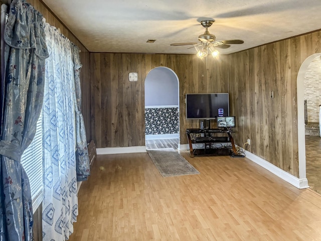 living room featuring light hardwood / wood-style floors, ceiling fan, and wooden walls