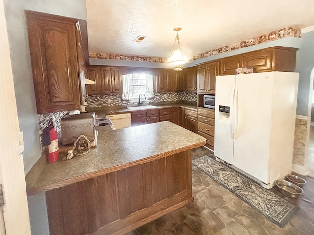 kitchen with kitchen peninsula, backsplash, white appliances, sink, and pendant lighting