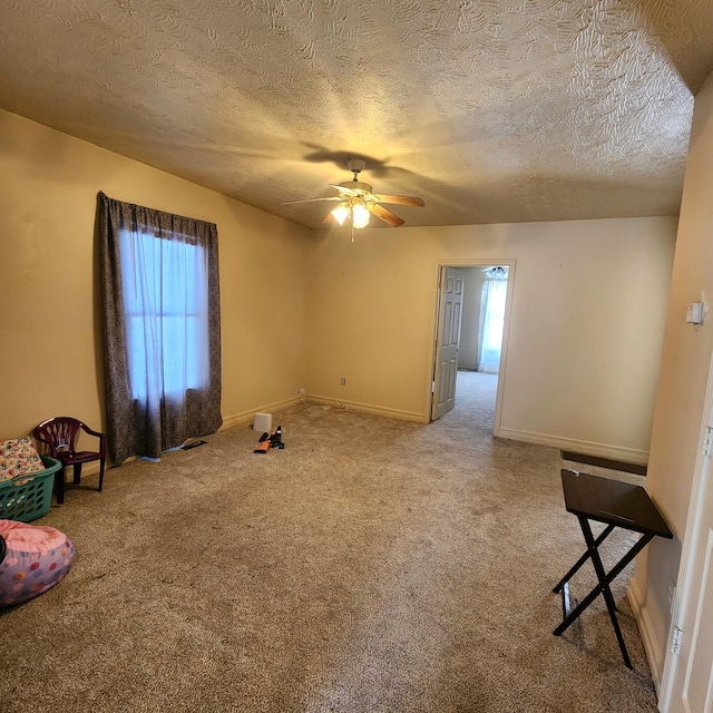 empty room with a textured ceiling, carpet floors, and ceiling fan