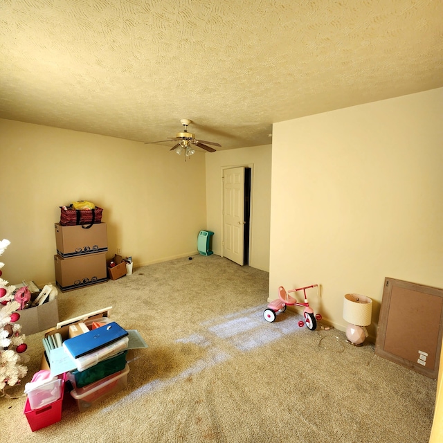 game room with a textured ceiling, ceiling fan, and carpet flooring